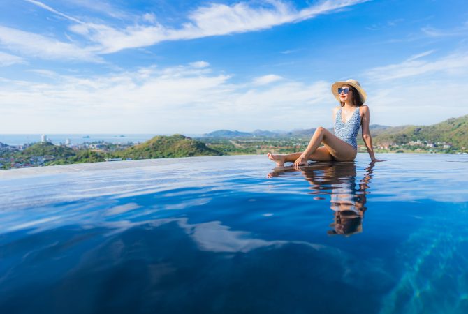 Portrait beautiful young asian woman smile happy relax around swimming pool in hotel resort for leisure travel and vacation concept